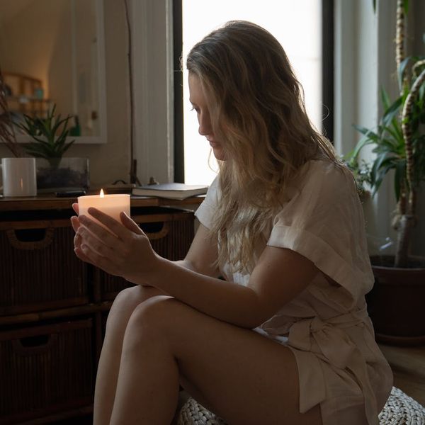 Cozy corner of a room with a yoga mat, plant, and candle.